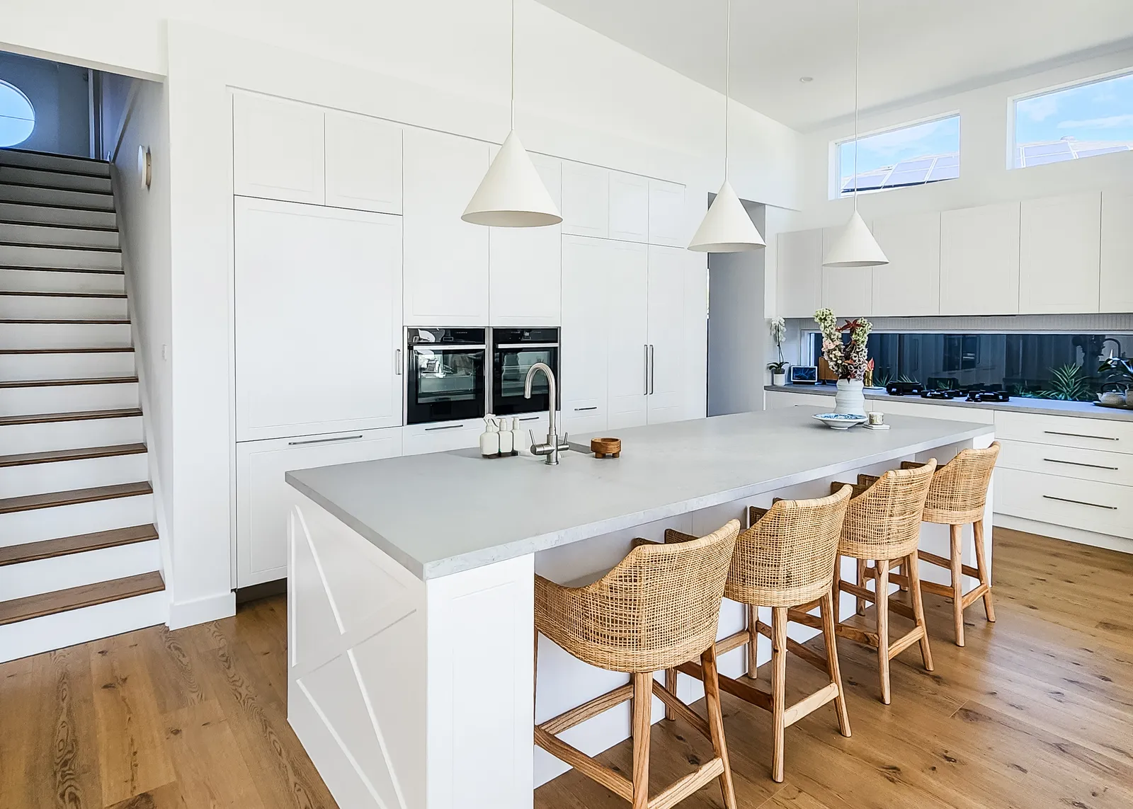 Custom home kitchen with stone island bench, pendant lights and timber floors