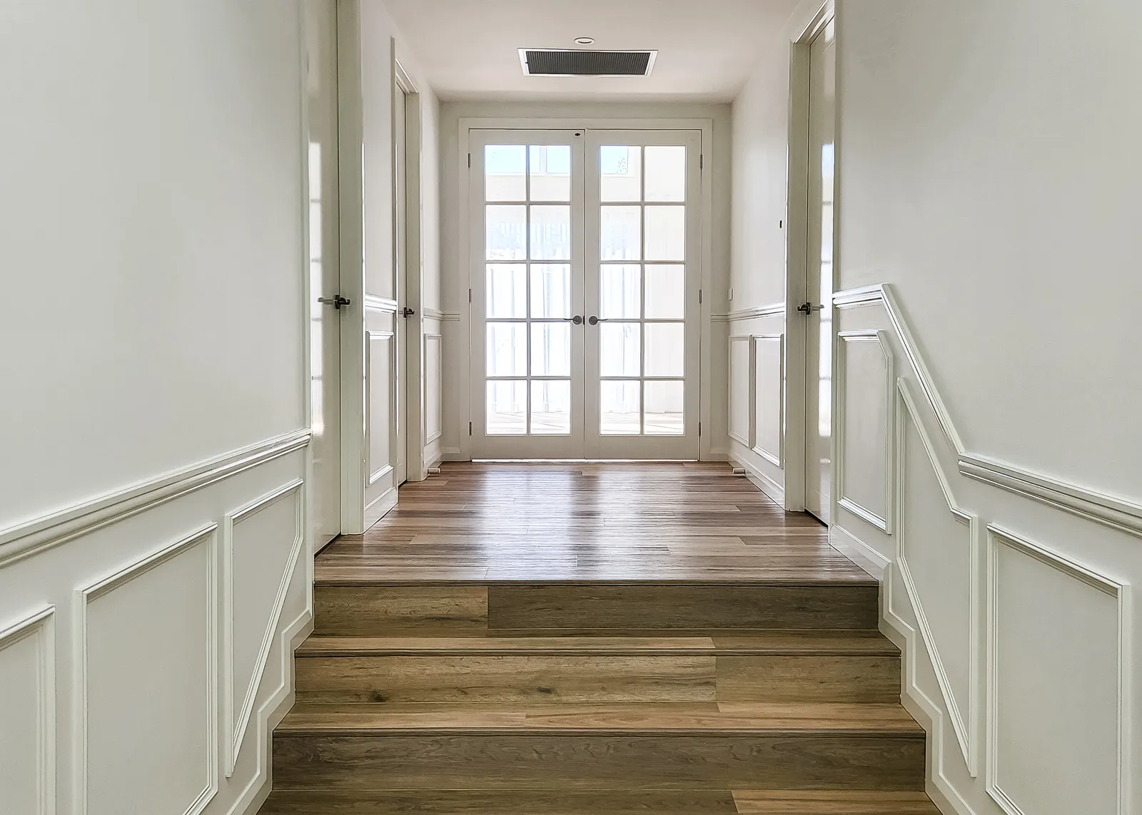 Custom home hallway with wainscoting and French doors