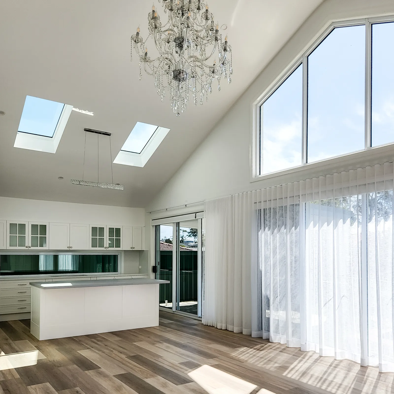 Vaulted living area with chandelier, skylights and open kitchen in a BuildTec luxury home